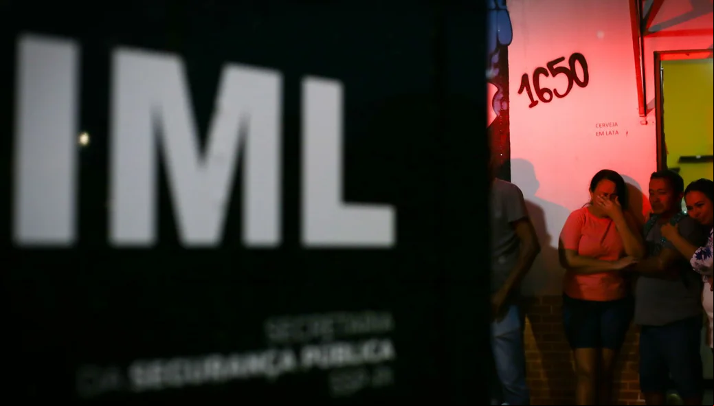 Familiares da vítima chorando enquanto IML remove corpo de vítima